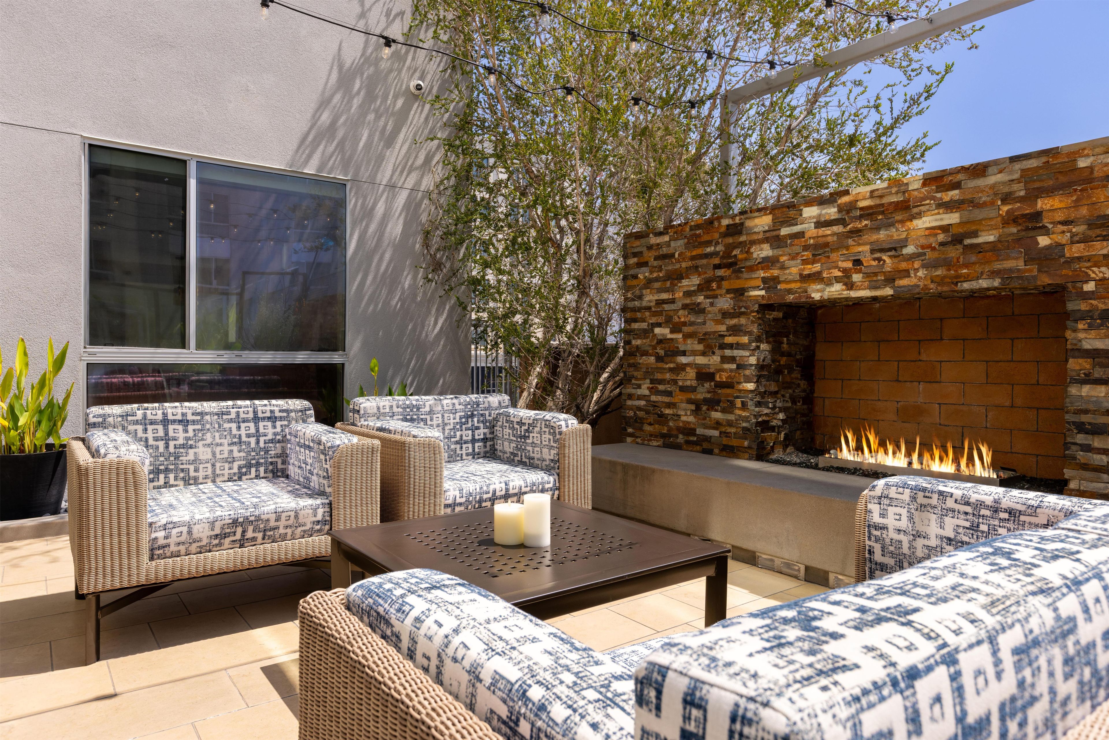 A patio with wicker furniture, a stone wall, and a fireplace.
