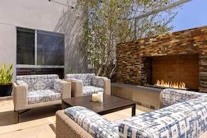 Un patio con mobiliario de mimbre, un muro de piedra y una chimenea.