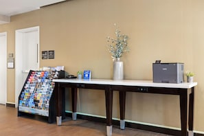 A reception desk with a printer, a vase with a plant, and a brochure stand. - Hampton Inn & Suites Los Angeles - Glendale (Glendale)