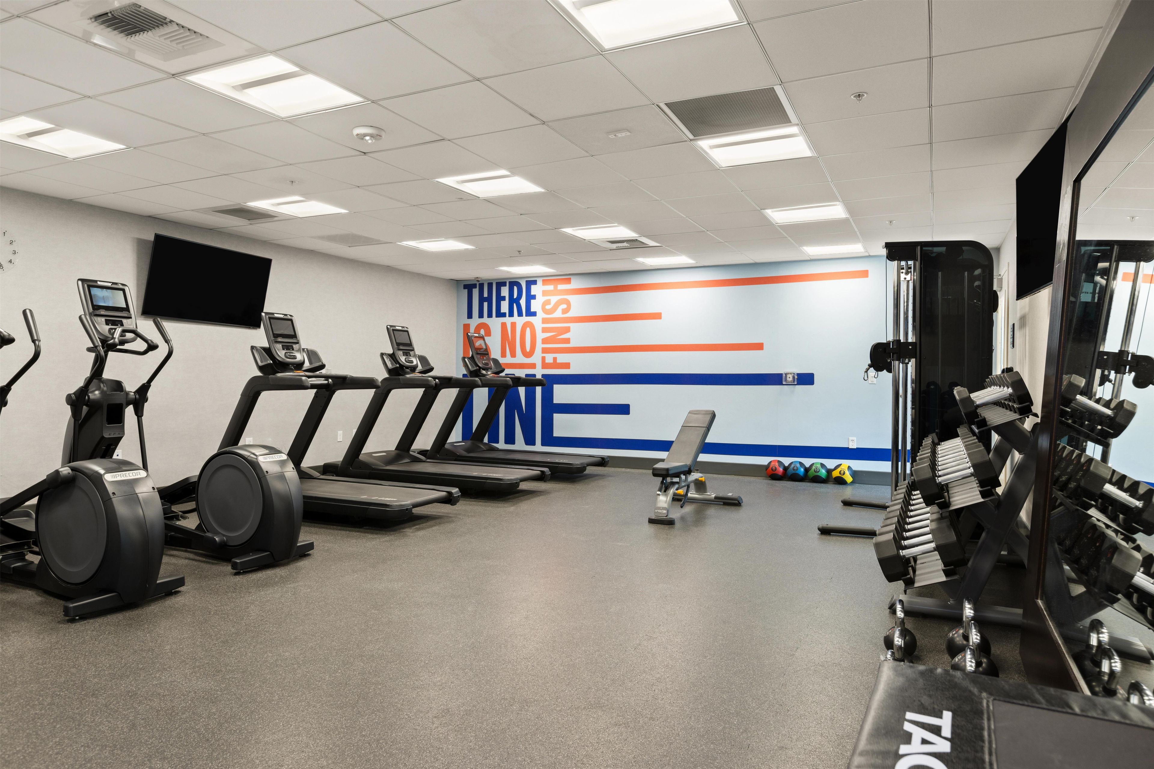 Ein Fitnessstudio mit Laufbändern, Crosstrainern und Gewichten.