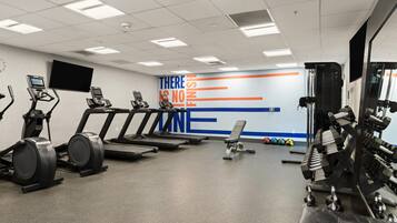 Ein Fitnessstudio mit Laufbändern, Crosstrainern und Gewichten.