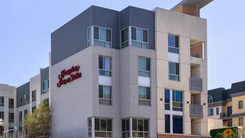 Modernilla tyylillä suunniteltu kerrostalohotelli, jossa on selkeästi näkyvä «Hampton Inn Suites» -kyltti, pysäköintialue ja avoin taivas.