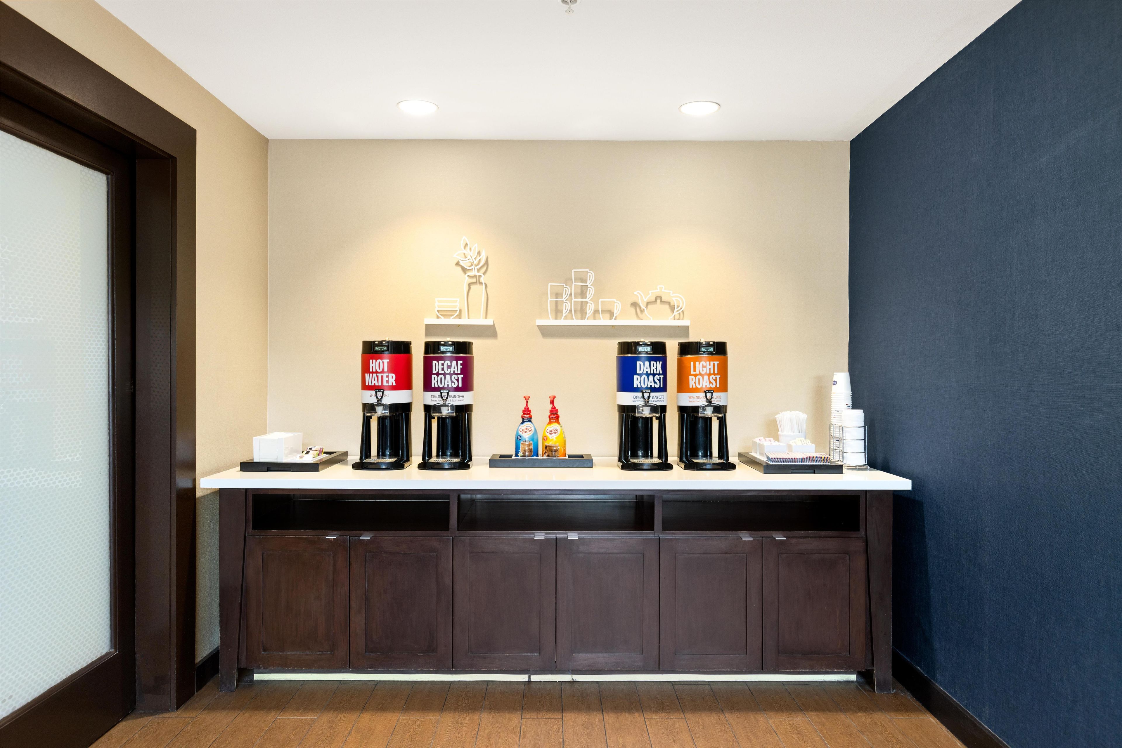 A hotel reception area with a coffee station featuring decaf, dark roast, and light roast options.