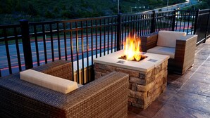An outdoor seating area with wicker furniture and a built-in fire feature. - Hampton Inn & Suites Pittsburgh Airport South–Settlers Ridge (Pittsburgh)