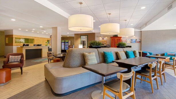 A modern hotel lobby with a reception desk, seating areas, and a dining space. - Home2 Suites by Hilton Waco (Waco)