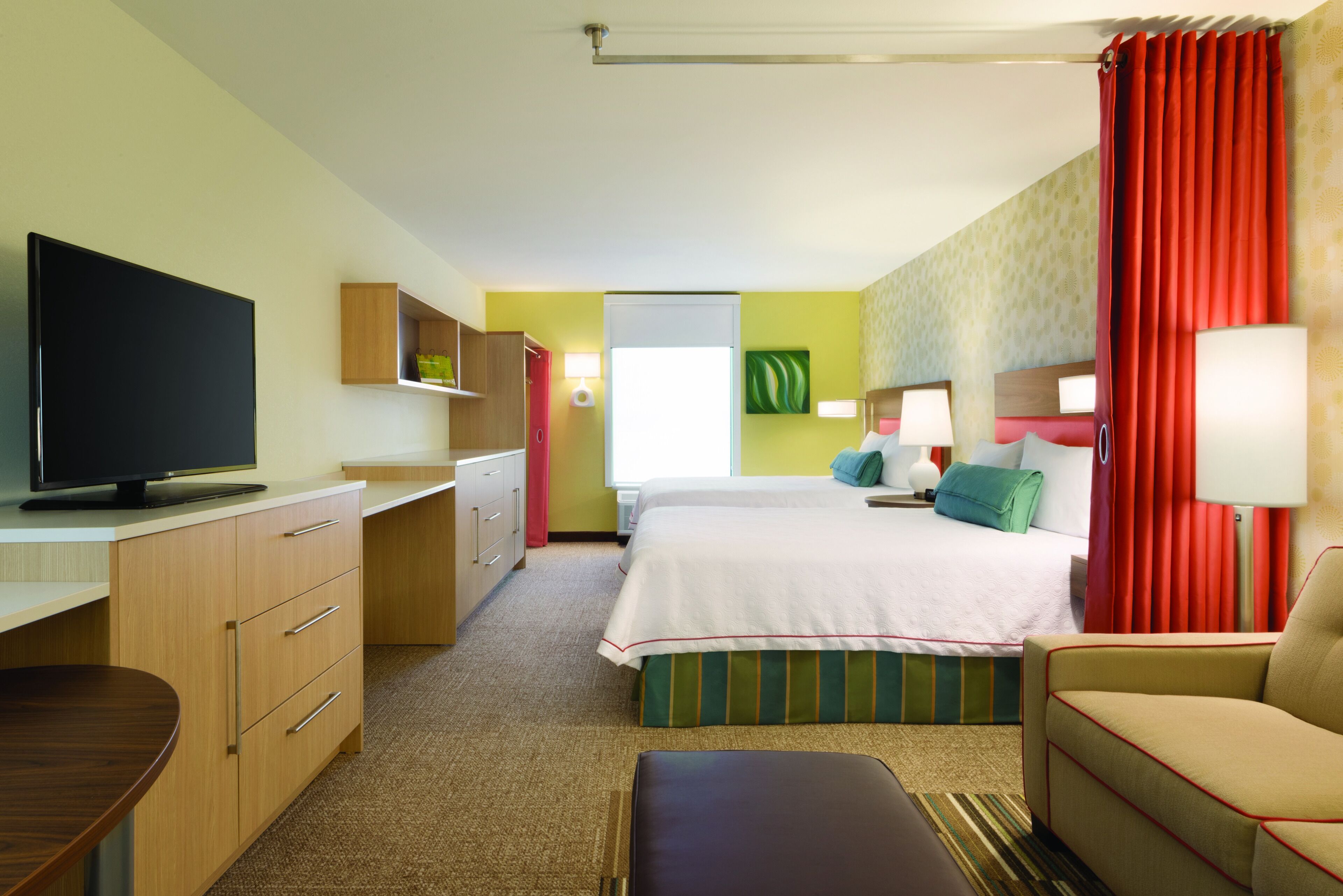 A hotel room with a bed, a desk, a television, and a couch.
