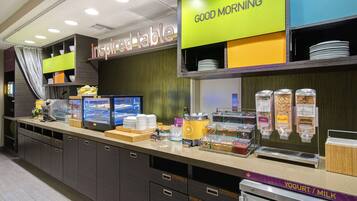A breakfast area with a self-serve station, a display for 'Good Morning', and a sign for 'Inspired Table'.