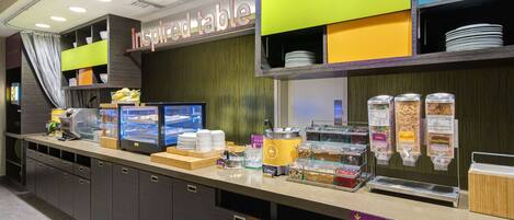 A breakfast area with a self-serve station, a display for 'Good Morning', and a sign for 'Inspired Table'.