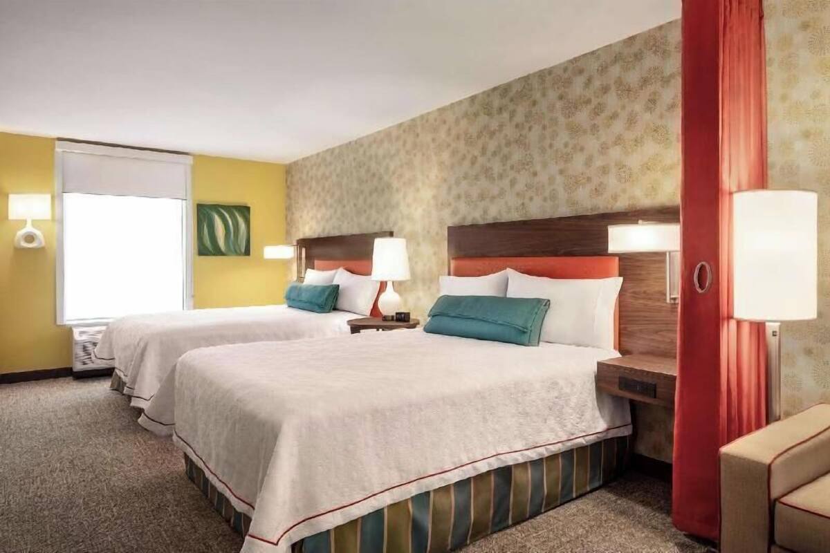 Ein Hotelzimmer mit zwei Betten, einem roten Vorhang und einem kleinen Sofa.
