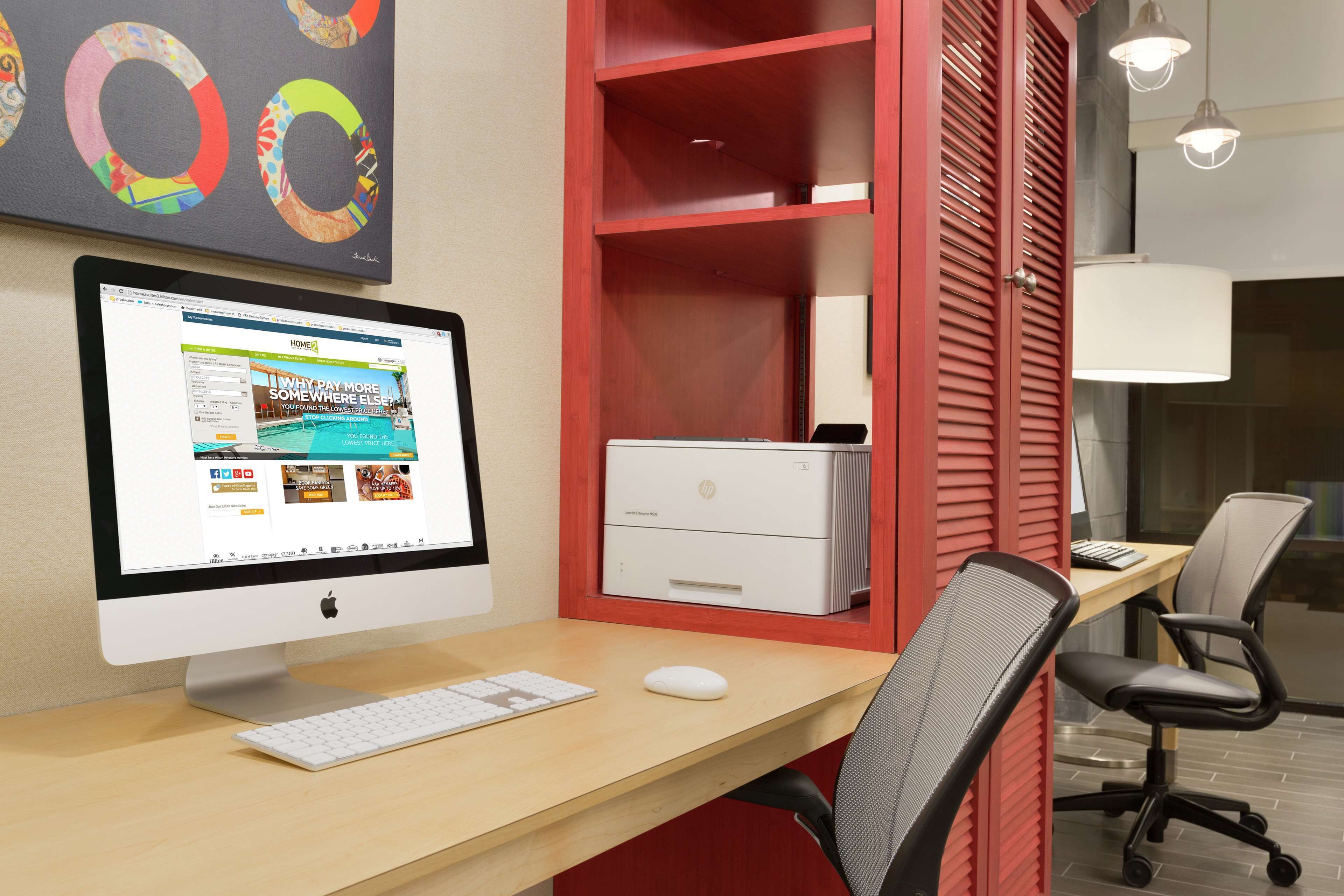 Um espaço de escritório moderno com um computador de mesa, uma impressora e cadeiras de escritório.
