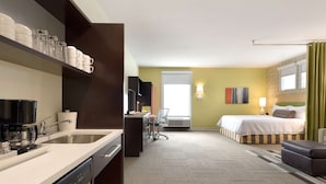 Une chambre d’hôtel équipée d’une kitchenette, d’un lit, d’un bureau et d’une chaise.