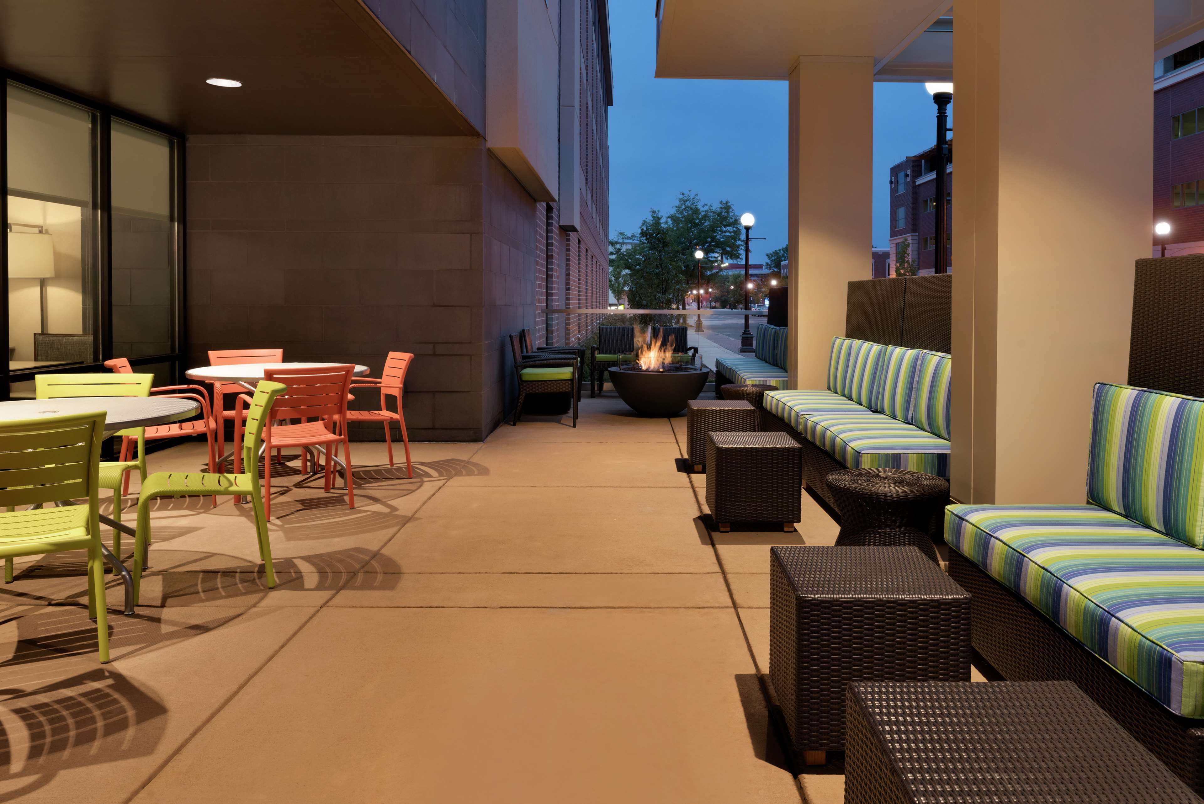 An outdoor patio area with seating arrangements, including tables and chairs, and a fire pit.