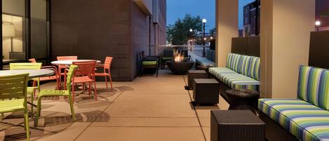 An outdoor patio area with seating arrangements, including tables and chairs, and a fire pit.