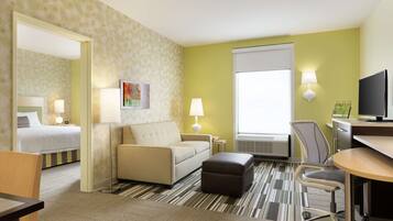 Une chambre d’hôtel comprenant un lit, un canapé, un bureau, une chaise et un téléviseur.