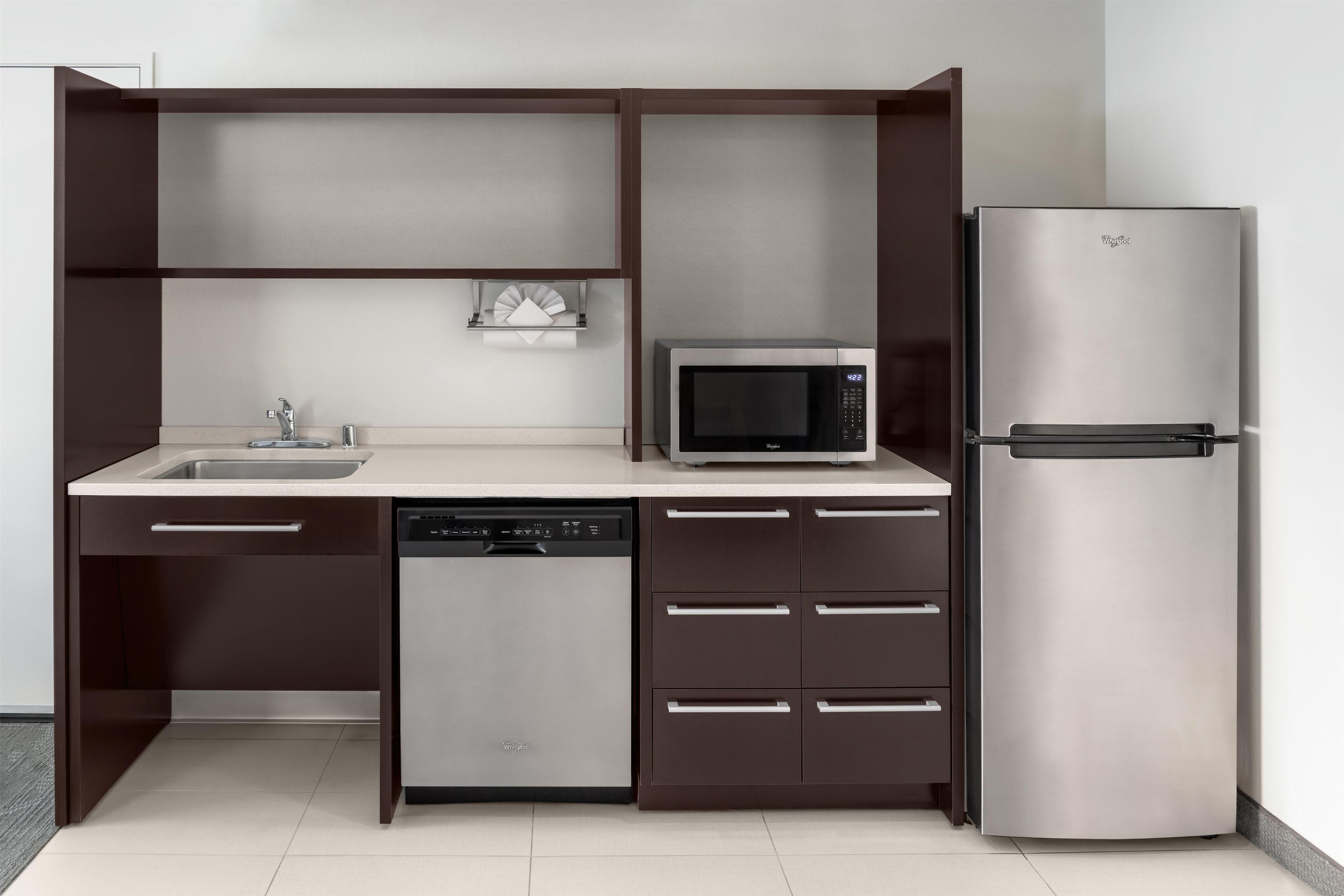 A compact kitchen with a dishwasher, microwave, and refrigerator.