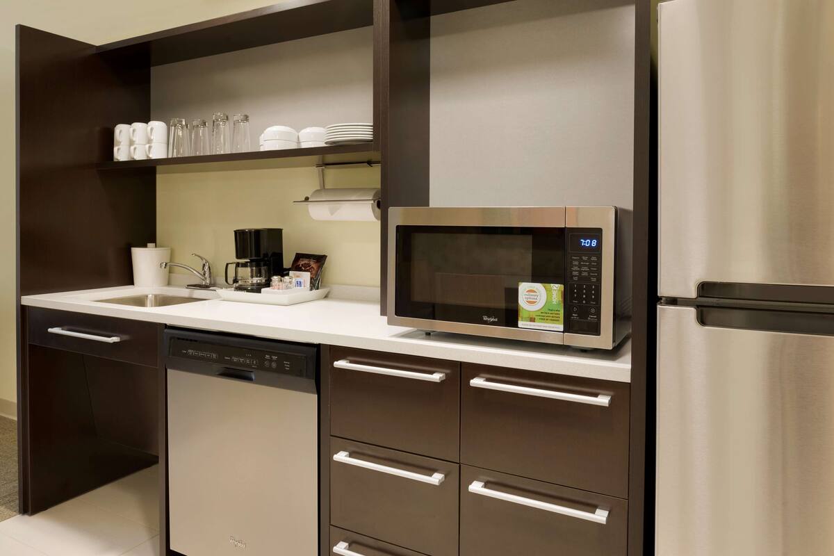 A modern kitchen with a stainless steel microwave, dishwasher, and refrigerator.