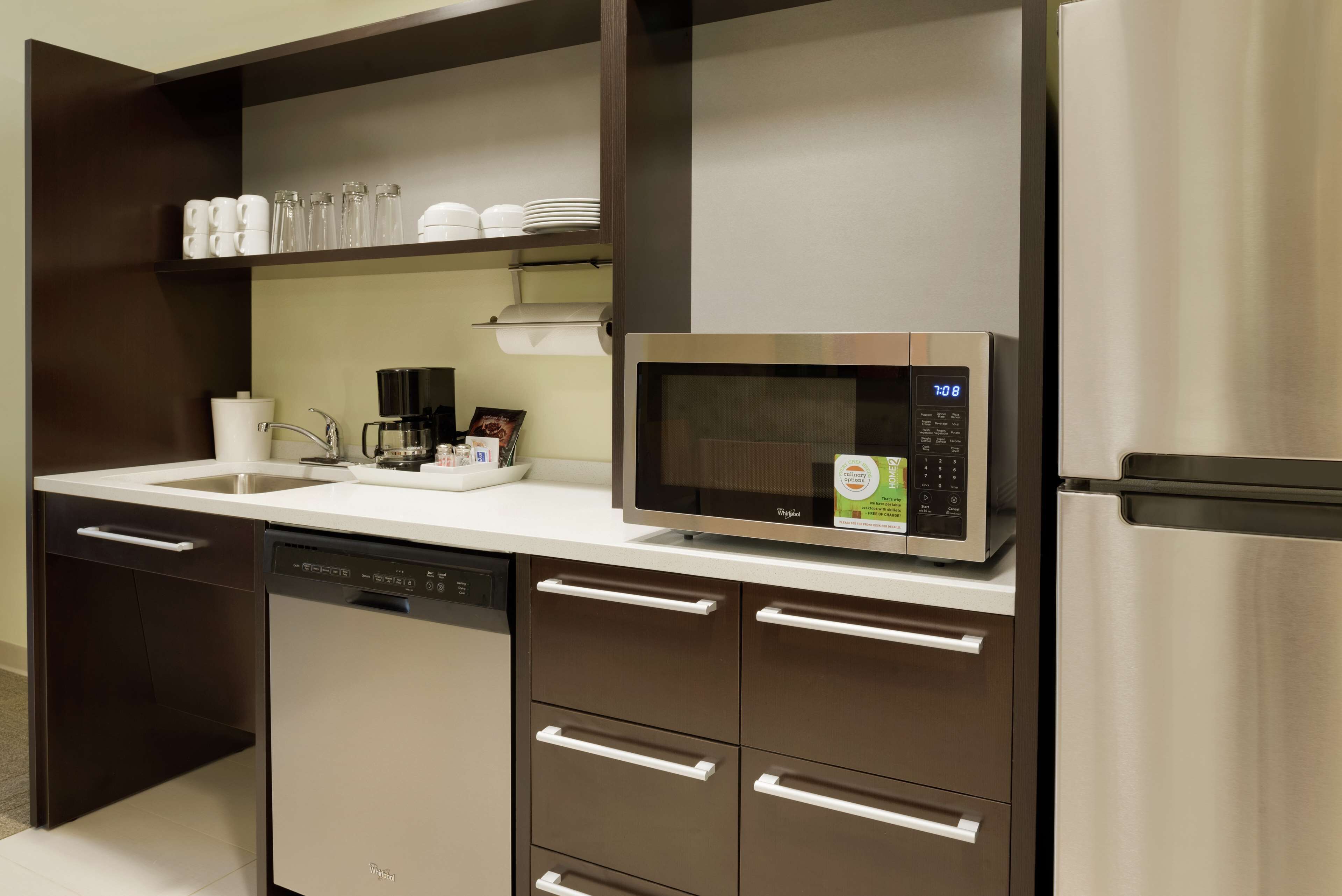A modern kitchen with a built-in microwave, dishwasher, and stainless steel refrigerator.