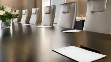 A conference room with a long table, several chairs, a vase with flowers, and a pen on the table.