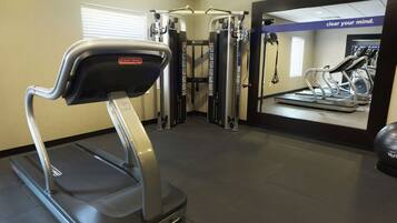 A gym with a treadmill, weight machines, and a wall with motivational text.
