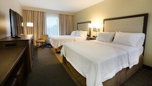 Une chambre d’hôtel avec deux lits, un bureau, une télévision et une lampe.
