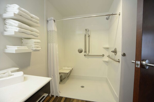 Une douche avec une porte en verre, un porte-serviettes avec des serviettes pliées et un plancher en bois.