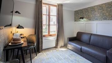 A modern living room with a leather sofa, a dining table with a lamp, and a patterned carpet.