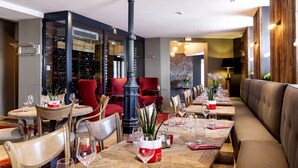 Un restaurante con una larga mesa de madera, sillas rojas y un pilar negro.