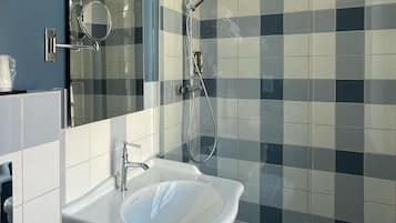 A bathroom with a white sink, a mirror, and a shower with a glass door.