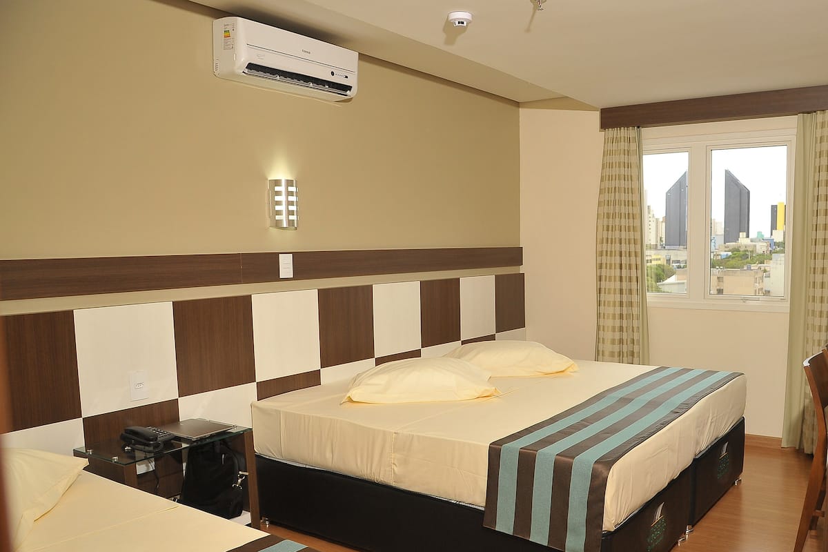 Een hotelkamer met een bed, een bureau en een raam met uitzicht op de stad.