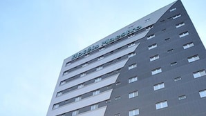 Un moderno edificio de hotel con varios pisos, grandes ventanales y un letrero llamativo en la parte superior.