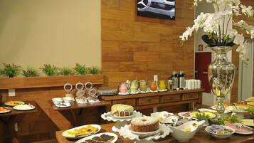 Buffet com diversos alimentos e uma televisão exibindo um anúncio de automóvel.