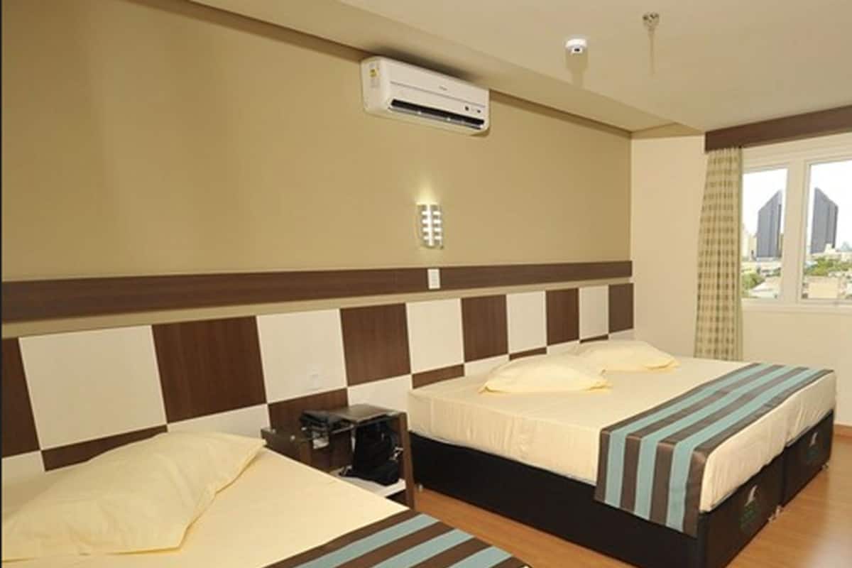 Een hotelkamer met twee bedden, een raam met gordijnen, een airconditioning en een wandlamp.