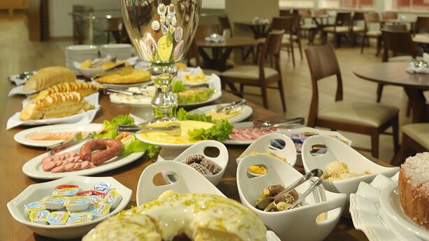 Una mesa de buffet con diversos platos, un jarrón decorativo con orquídeas y un área de comedor con sillas y mesas.