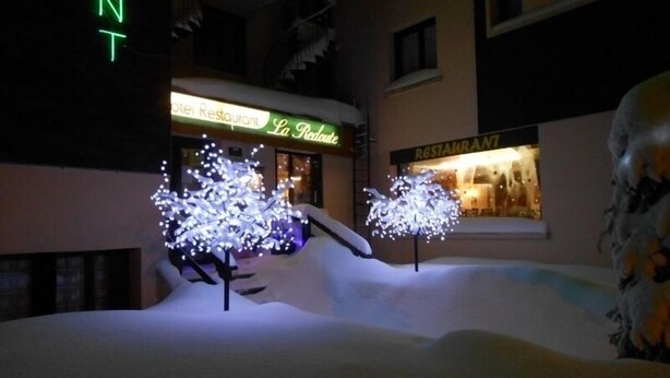 Un hotel con árboles iluminados y un letrero de restaurante.