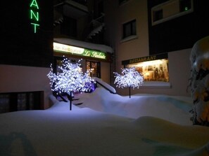 Un hotel con árboles iluminados y un letrero de restaurante.