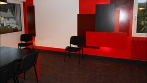 Un salón de conferencias con una pizarra, dos sillas negras y una pared de acento roja.