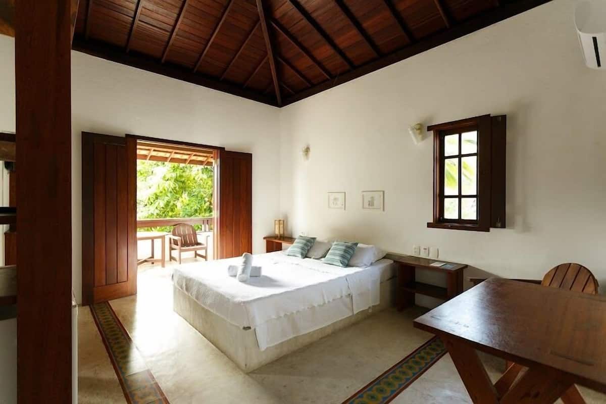 A bedroom with a bed, bedside table, and a window.