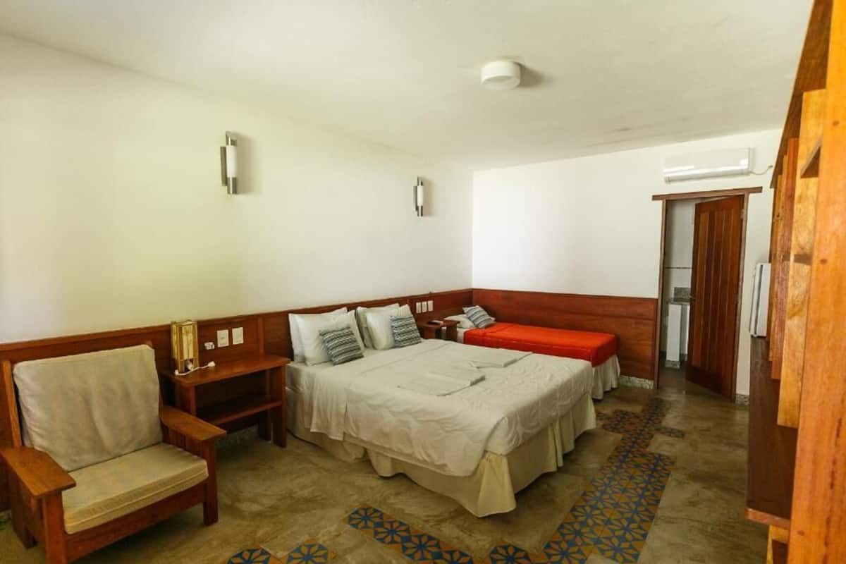 A bedroom with a bed, a wooden bench, a sofa, and a small table.