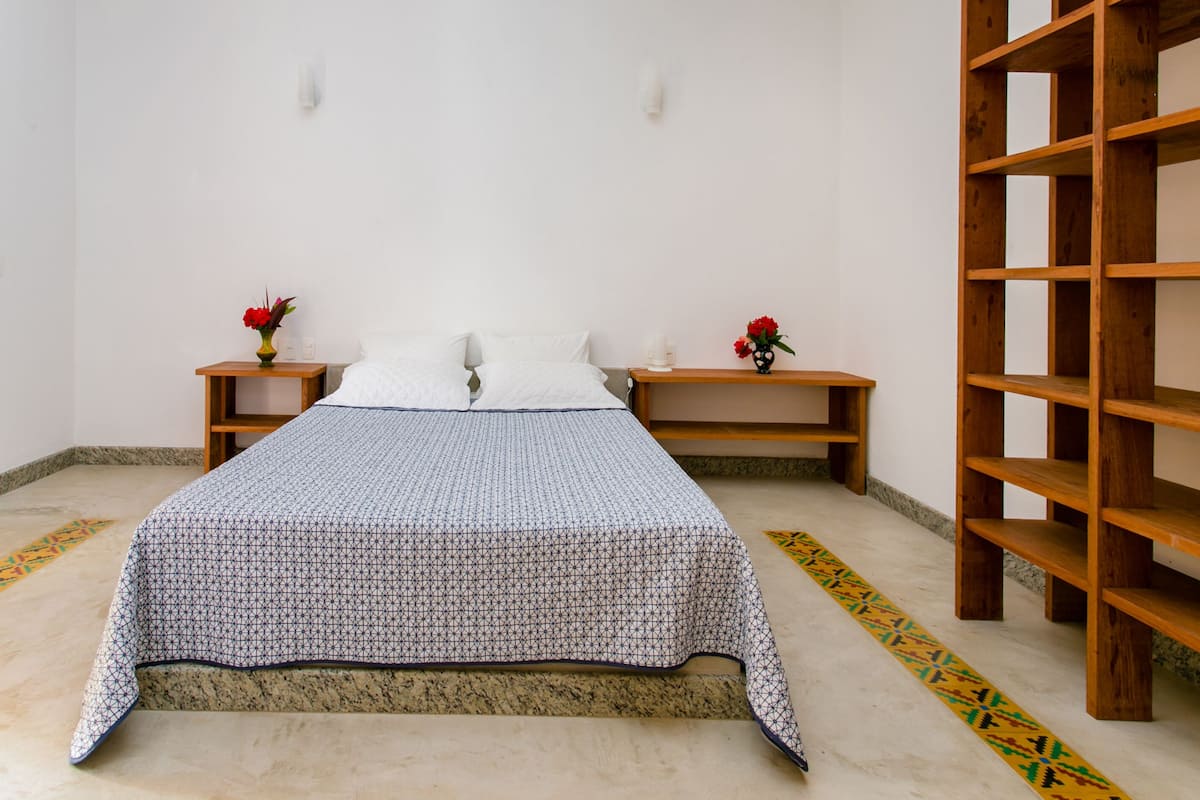 A bedroom with a bed, wooden nightstands, and a wooden shelf unit.
