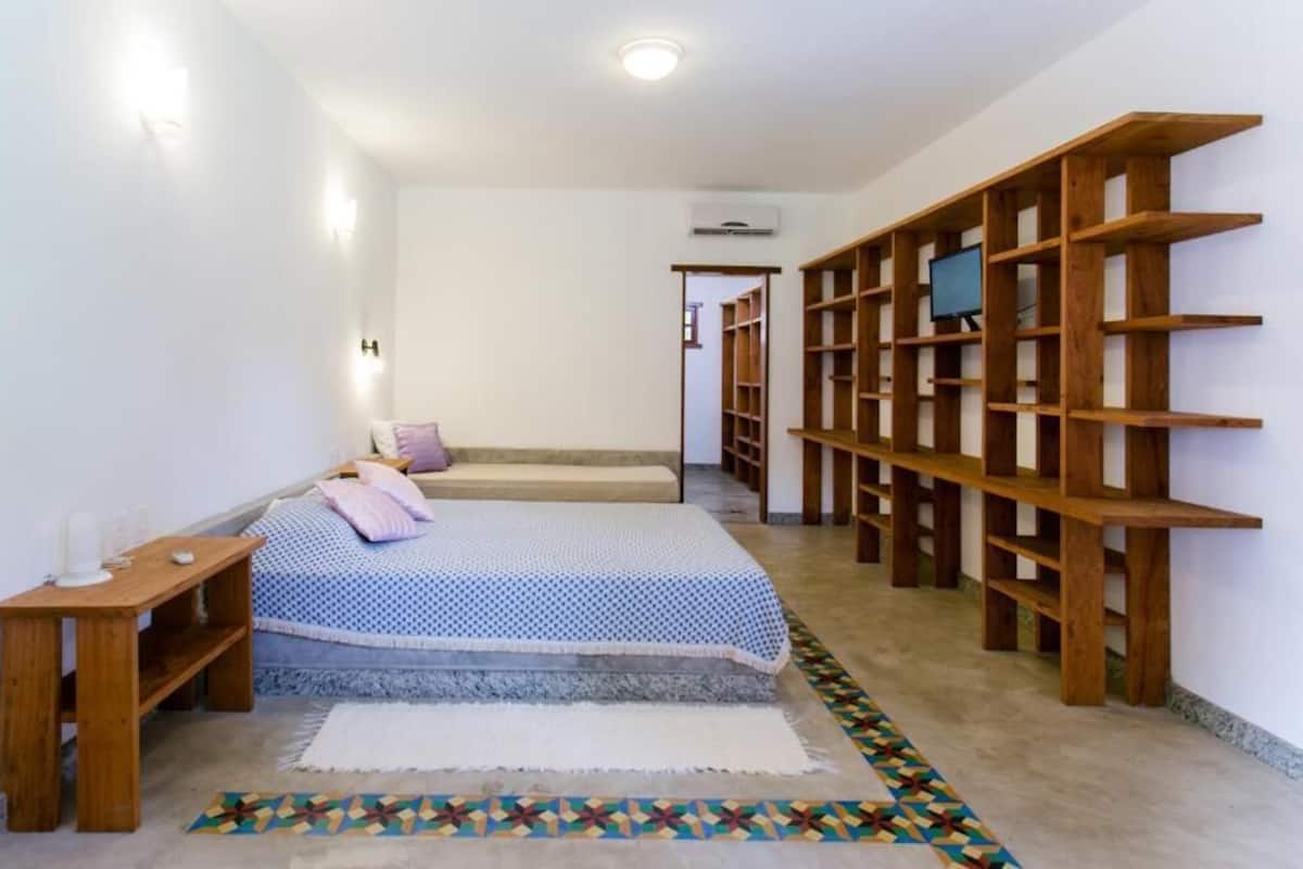A bedroom with a bed, bedside table, and a wooden bookshelf.