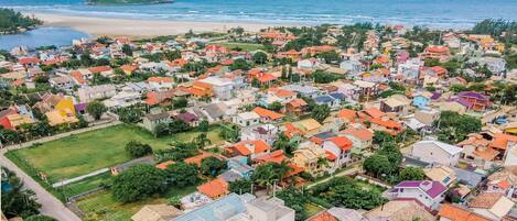 An aerial view of a coastal town with colorful houses, a beach, and a small island in the distance.