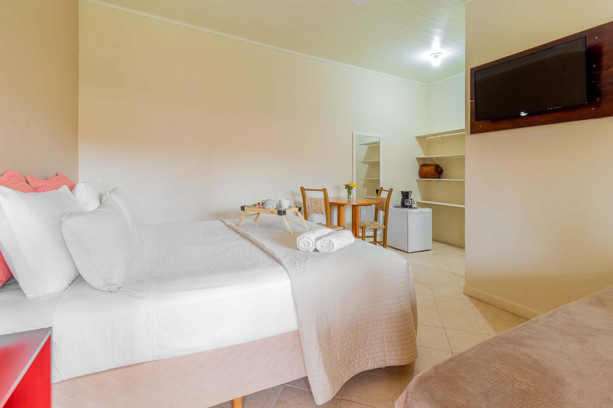 Habitación de hotel con cama, escritorio, silla, televisor y estante.
