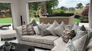 Ein modernes Wohnzimmer mit einem Ecksofa, einem schwarzen Couchtisch und Blick auf einen Garten.