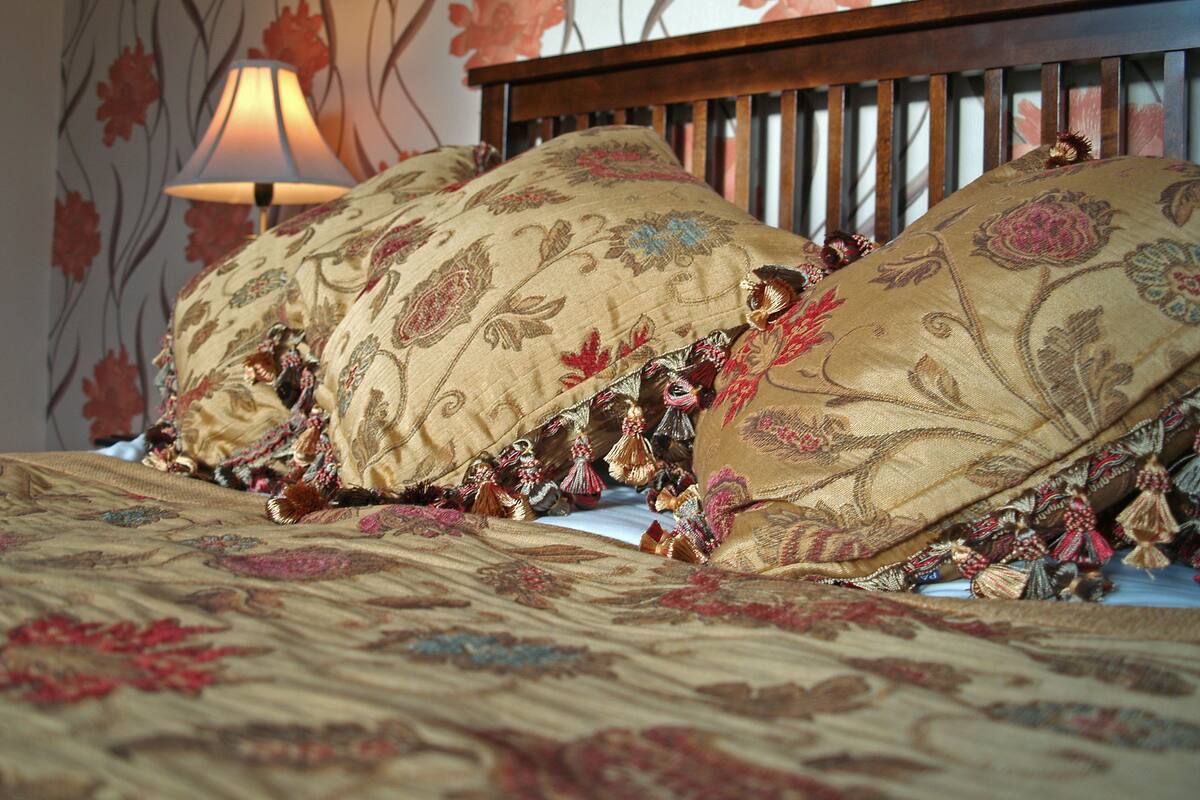 A bed with ornate pillows and a decorative lamp.