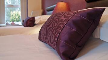 A neatly made bed with a patterned pillow and a plain pillow in a hotel room.