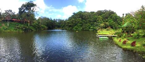 A serene riverside setting with a small boat docked near the shore, surrounded by lush greenery and a few buildings in the background.
