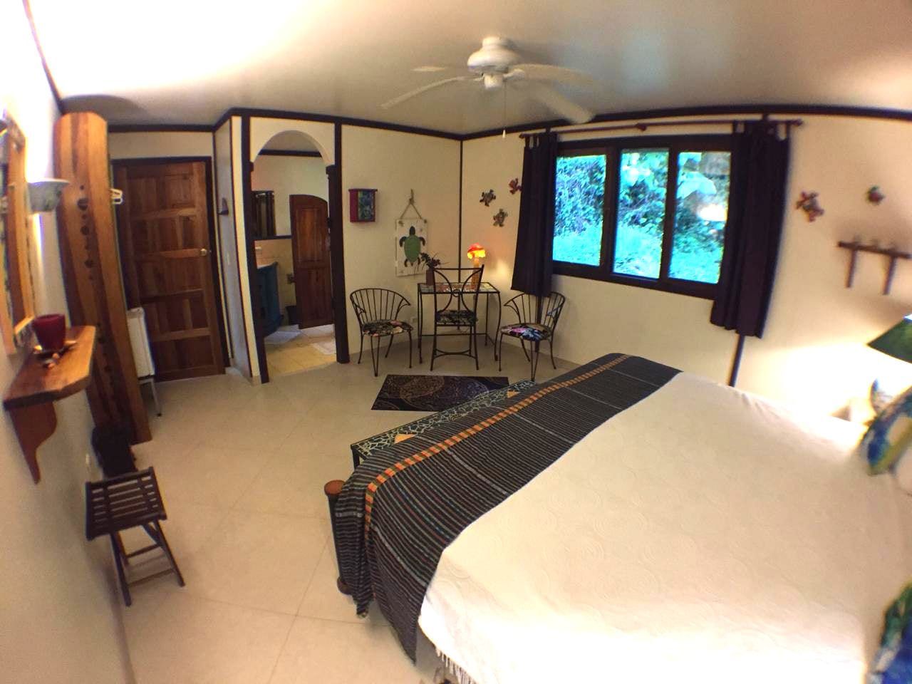 A bedroom with a bed, a desk, a chair, and a dining table.