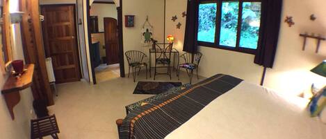 A bedroom with a bed, a desk, a chair, and a dining table.