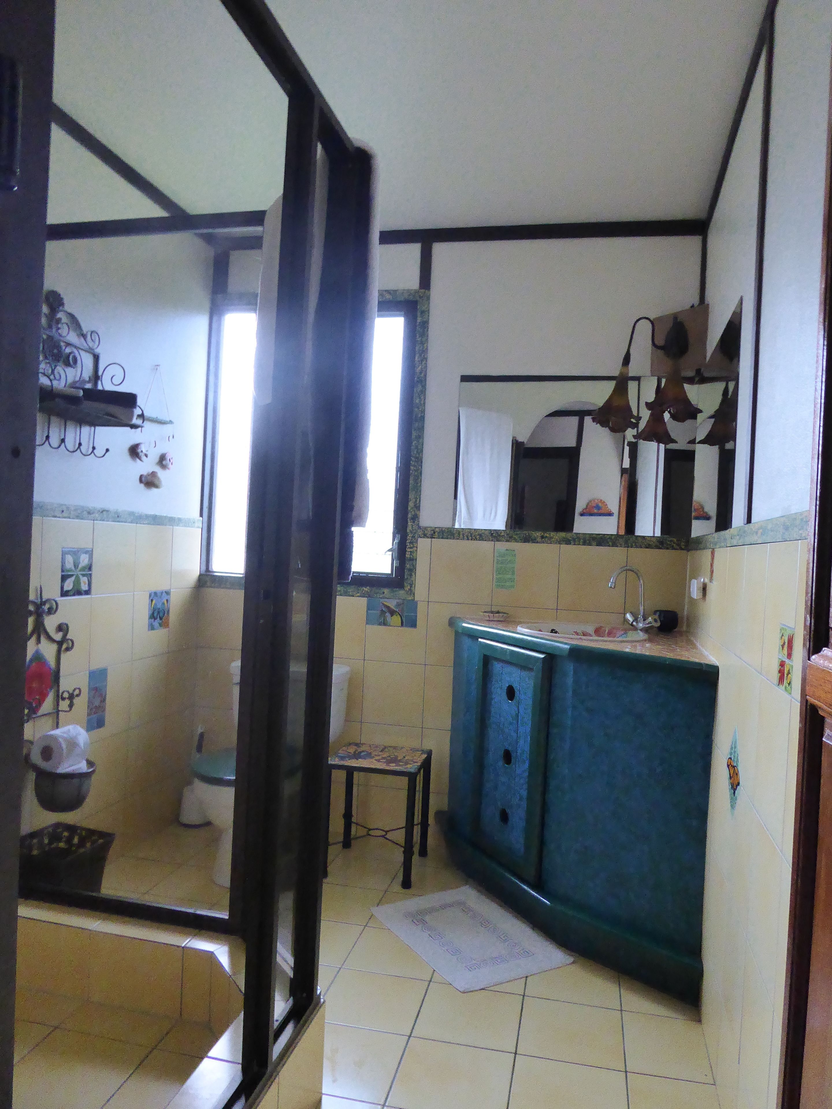 Cocina pequeña y funcional con lo esencial, como un lavamanos, un taburete y una ventana que proporciona luz natural.