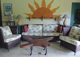 Una sala de estar con un conjunto de sofá, una mesa de centro de madera única y un mural en la pared.